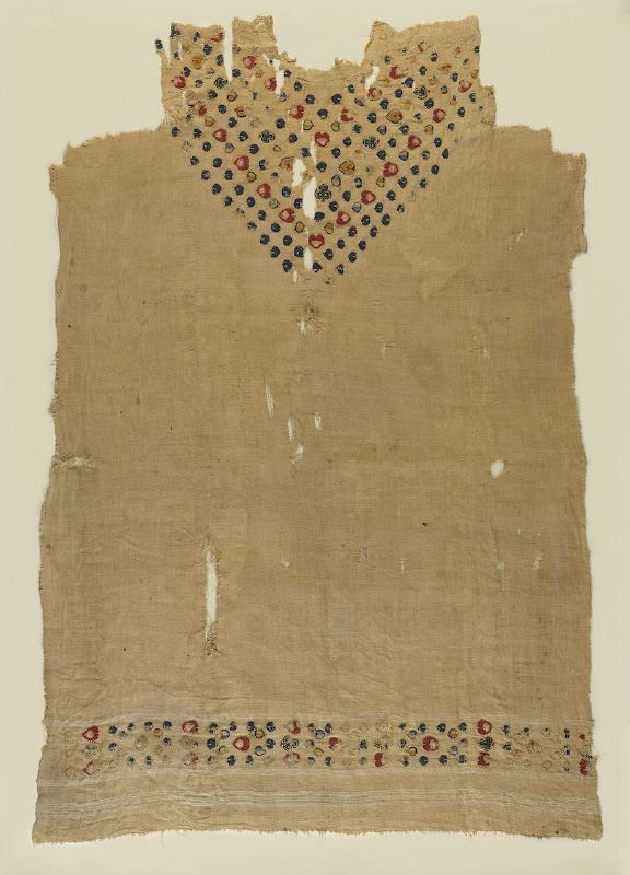 Tunic with floral motifs at neck and bottom edge, plain (tabby) ground weave, tapestry band of dyed wools of floral motifs at lower edge and forming “v” at neck (Egypt, c5th –6th century CE) 